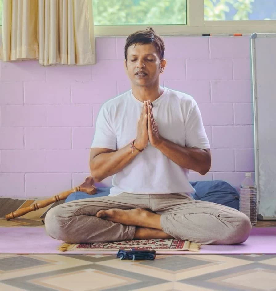 Somashekar, founder and head teacher of Anantadrishti Yoga, seated with palms together in namaste in Rishikesh