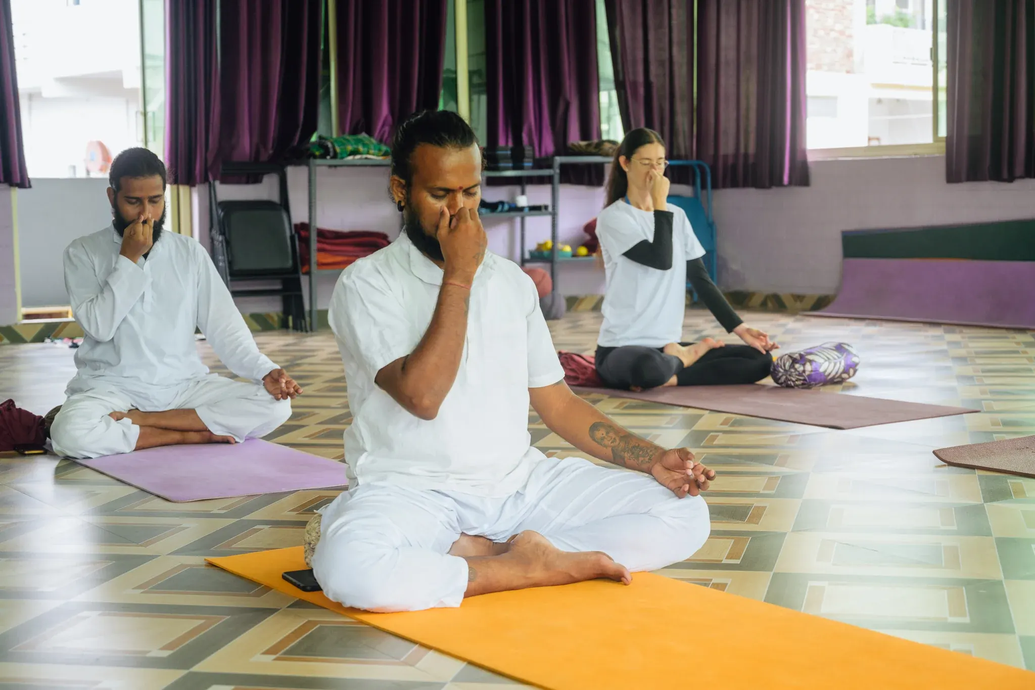 Students practice Nadi Shodhana alternate nostril breathing on mats in a Rishikesh pranayama class